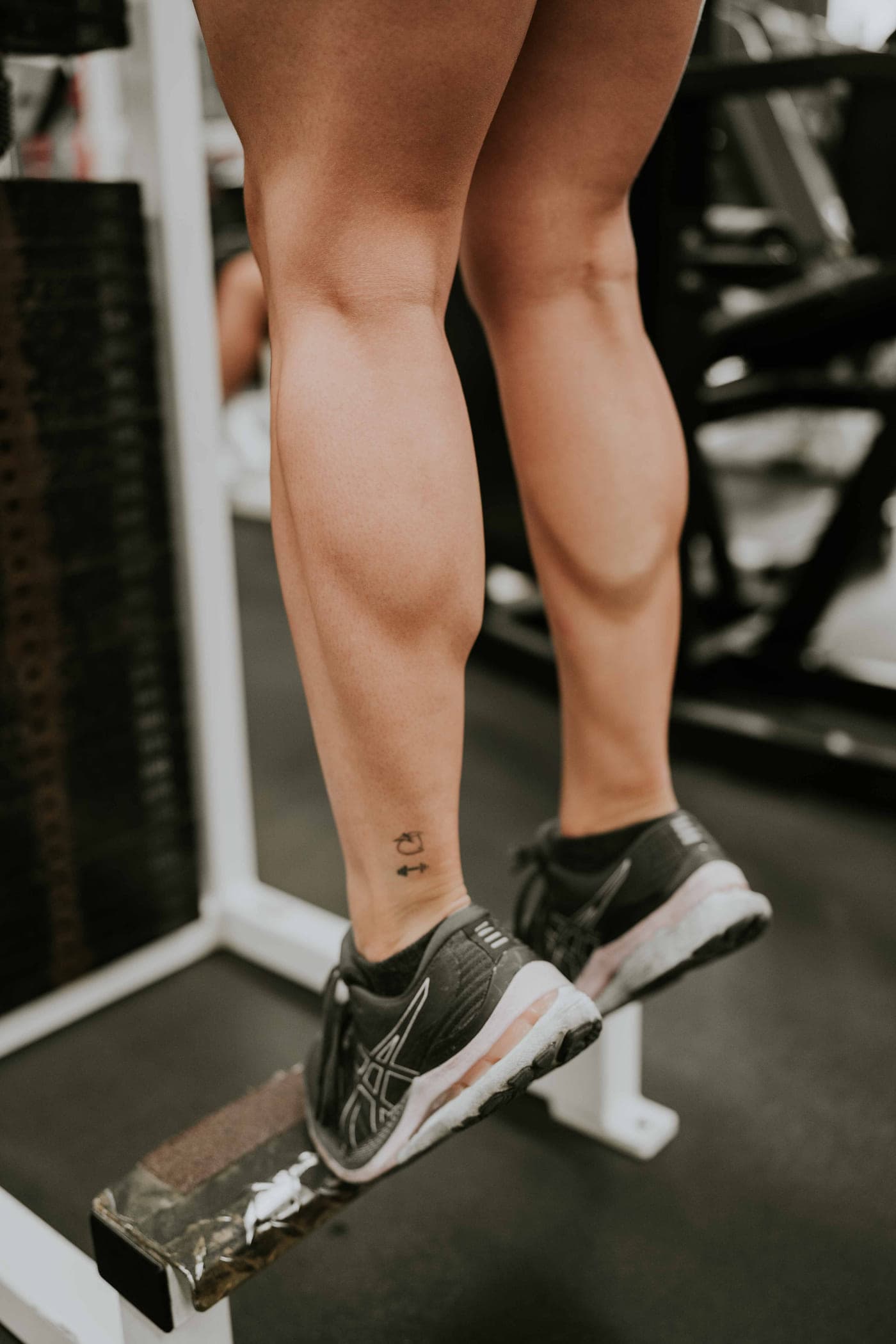 Close-up of calves on a raised block with the heels lowered below the step.